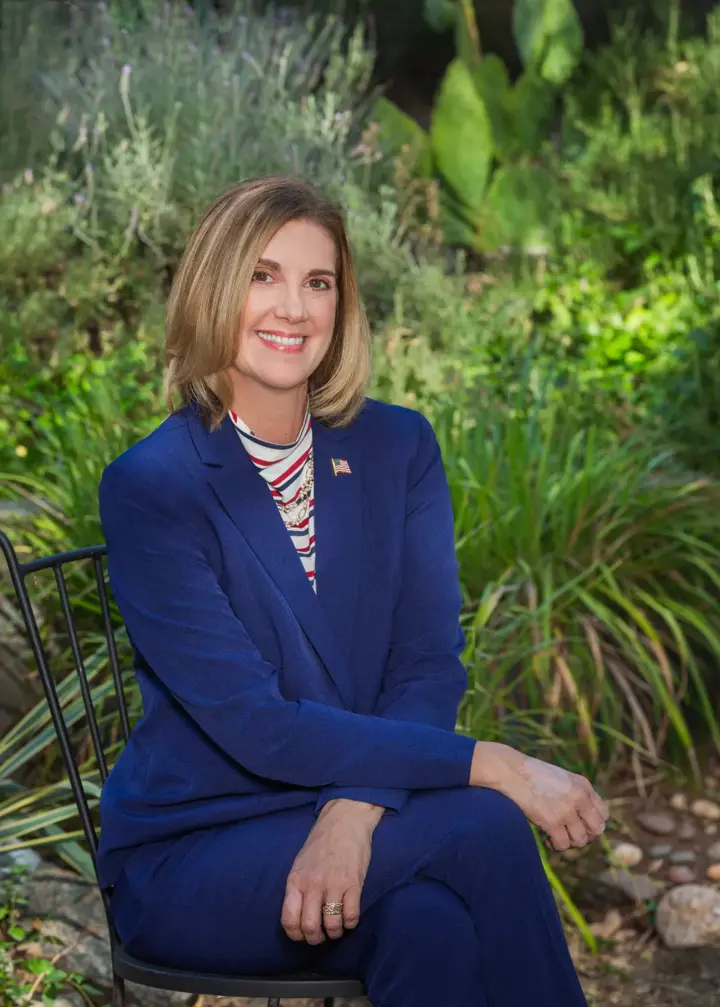 Portrait of Mel Barker in a navy suit, seated in a Madera County garden